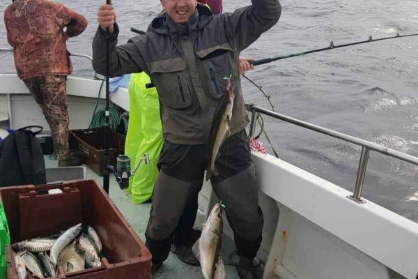 Angling_09 man smiling holding up rod with three caught fish